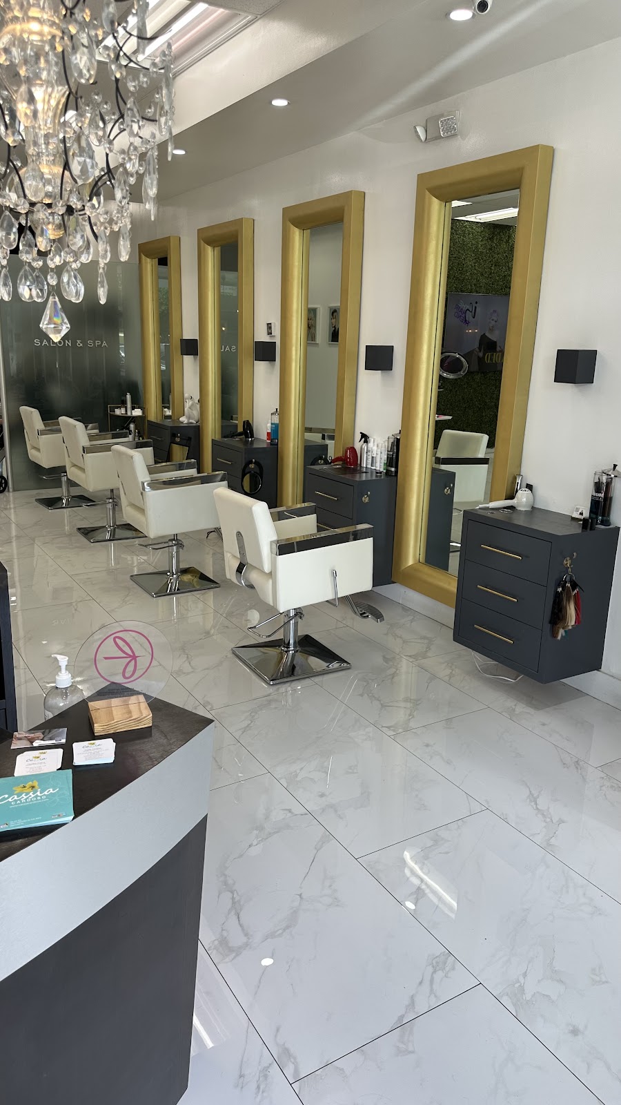 Styling stations with gold-framed mirrors and marble floors
